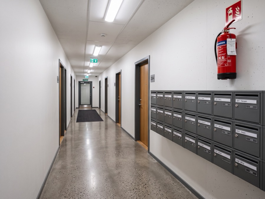 Felles korridor i leilighetsbygg med postkasser og brannslukker